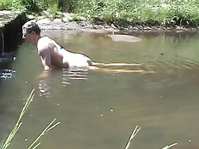 Cumming atop a stone in a river